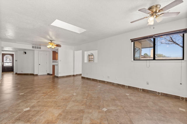 5812 Alegria Rd NW, Albuquerque, NM 87114 - unfurnished living room featuring a textured ceiling, a ceiling fan, baseboards, a skylight, and visible vents