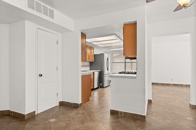 5812 Alegria Rd NW, Albuquerque, NM 87114 - kitchen featuring brown cabinetry, visible vents, light countertops, baseboards, and stainless steel appliances