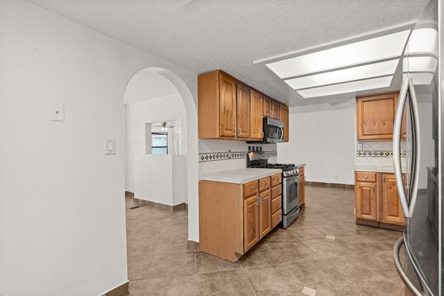 5812 Alegria Rd NW, Albuquerque, NM 87114 - kitchen with light countertops, tasteful backsplash, arched walkways, light tile patterned floors, and stainless steel appliances