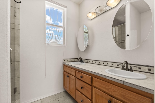 bathroom with double vanity, a tile shower, and a sink