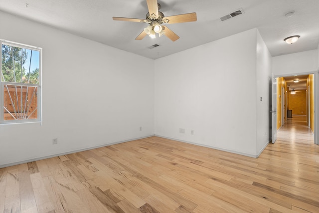empty room featuring baseboards, ceiling fan, light wood-style flooring, and visible vents