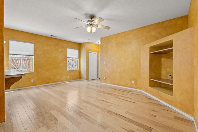spare room with wood-type flooring, a textured ceiling, ceiling fan, and visible vents
