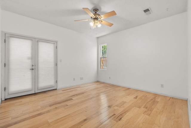 spare room with a ceiling fan, wood finished floors, and visible vents