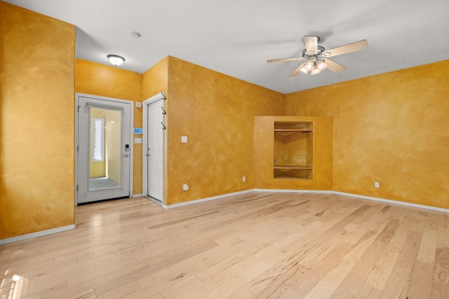 spare room featuring baseboards, ceiling fan, and light wood-style flooring
