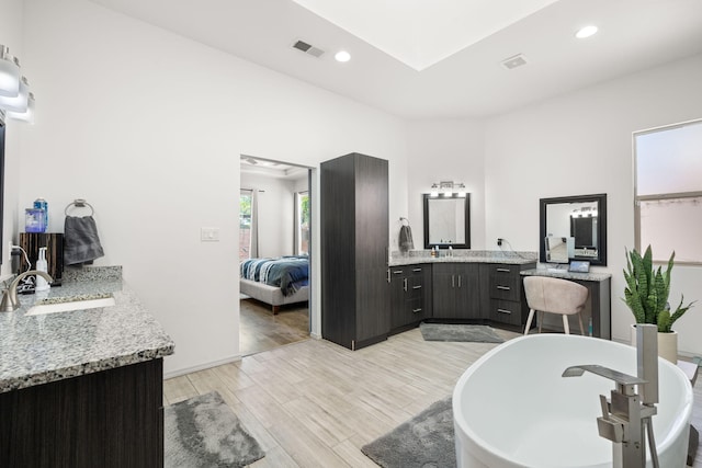 ensuite bathroom featuring visible vents, a freestanding tub, wood finished floors, ensuite bathroom, and a sink
