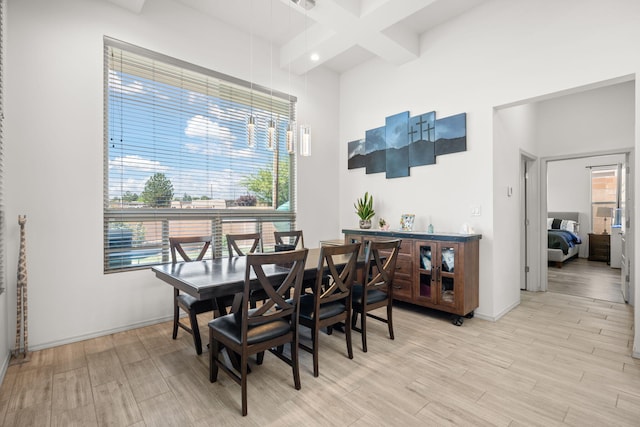 dining area featuring beamed ceiling, baseboards, and light wood finished floors