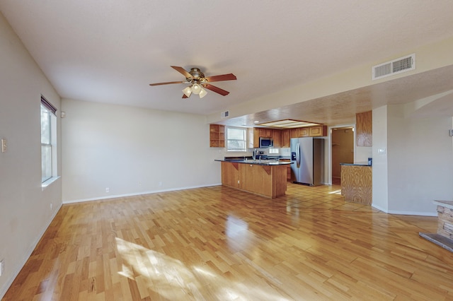 kitchen with light wood-type flooring, stainless steel appliances, a peninsula, and visible vents