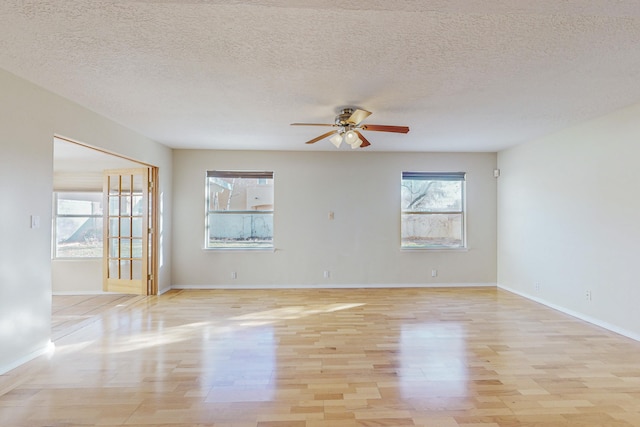 empty room featuring baseboards, a ceiling fan, and light wood-style flooring