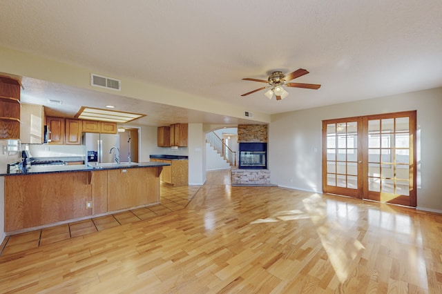kitchen with a peninsula, open floor plan, visible vents, and light wood finished floors