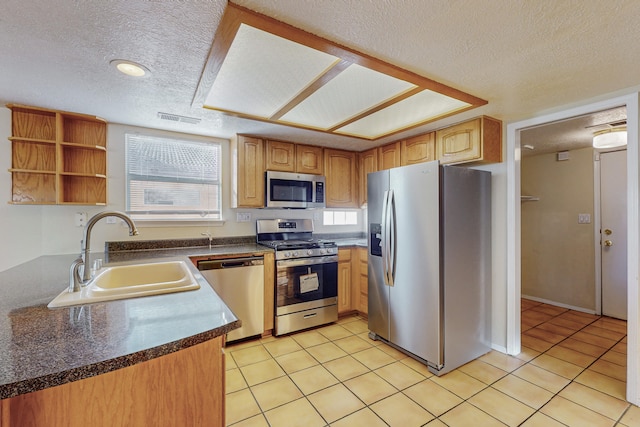 kitchen with visible vents, dark countertops, a textured ceiling, a sink, and appliances with stainless steel finishes