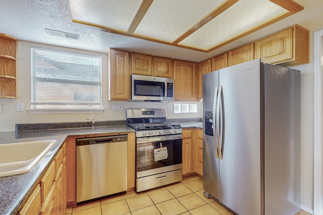 kitchen with a sink, plenty of natural light, stainless steel appliances, and light tile patterned flooring