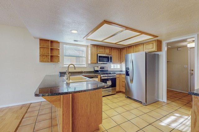 kitchen featuring open shelves, a sink, a textured ceiling, stainless steel appliances, and a peninsula