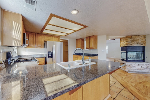 kitchen featuring a textured ceiling, visible vents, stainless steel fridge, and a sink