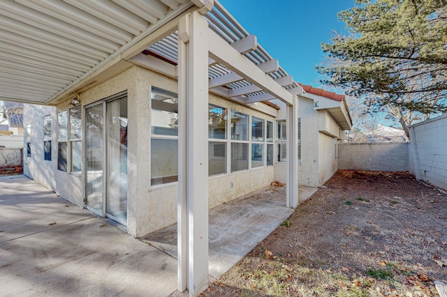 view of side of home featuring a patio, stucco siding, fence, and a pergola