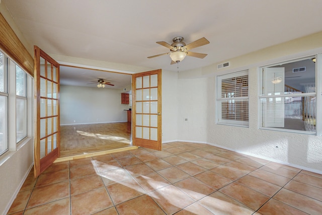 tiled spare room featuring visible vents, baseboards, ceiling fan, and french doors