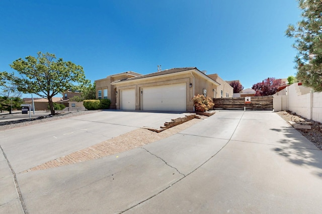 4954 Dream Dancer Dr NE, Rio Rancho, NM 87144 - view of side of property featuring stucco siding, a garage, fence, and driveway