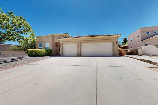 view of front facade featuring concrete driveway, a tiled roof, stucco siding, and a garage