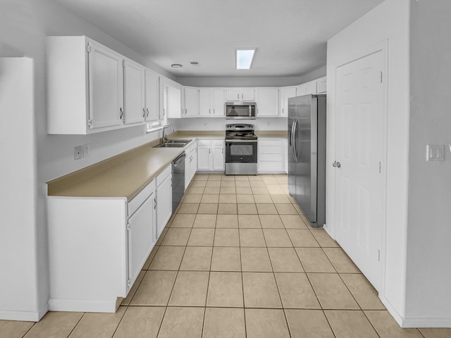 kitchen with white cabinets, appliances with stainless steel finishes, a sink, light countertops, and light tile patterned floors