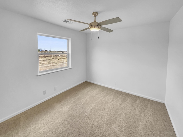carpeted spare room featuring visible vents, baseboards, and ceiling fan