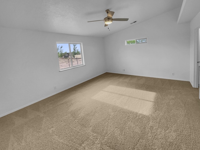 carpeted empty room with ceiling fan, visible vents, and baseboards