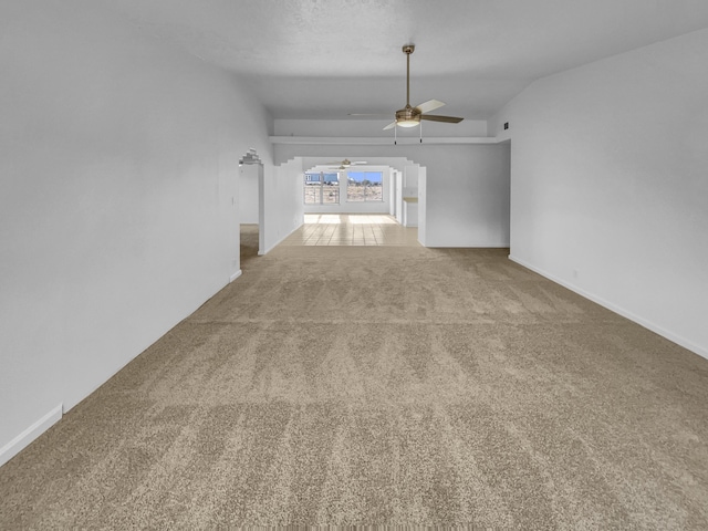 carpeted empty room with ceiling fan, vaulted ceiling, and baseboards