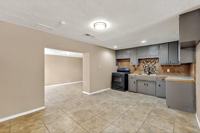 7121 Isleta Blvd SW Rear, Rear, Albuquerque, NM 87105 - kitchen with black gas range oven, gray cabinets, decorative backsplash, light countertops, and baseboards