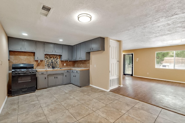 7121 Isleta Blvd SW Rear, Rear, Albuquerque, NM 87105 - kitchen with black gas range oven, gray cabinetry, light tile patterned floors, tasteful backsplash, and baseboards