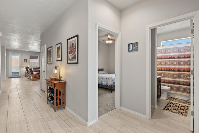 corridor featuring baseboards and a textured ceiling