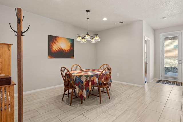 dining room with an inviting chandelier, a textured ceiling, baseboards, and visible vents