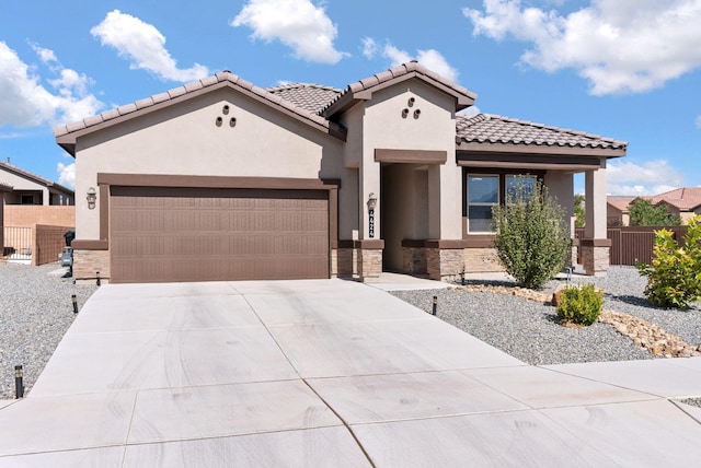 mediterranean / spanish home with an attached garage, concrete driveway, stucco siding, and stone siding