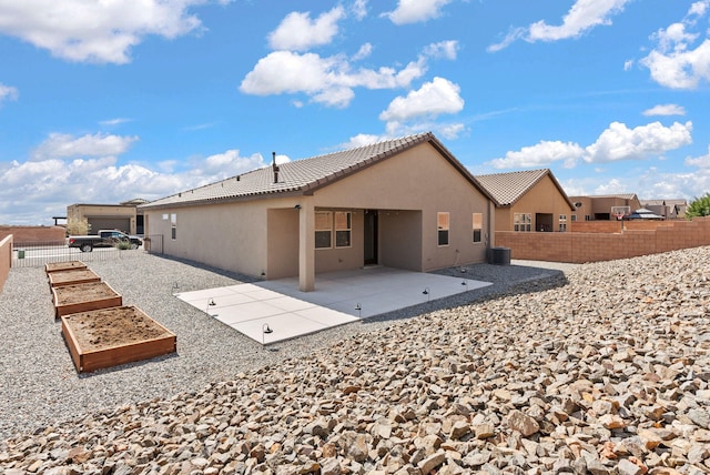 back of house with stucco siding, a fenced backyard, a garden, a patio, and a tiled roof