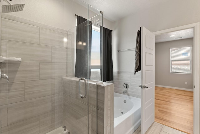bathroom featuring a textured ceiling, baseboards, a shower stall, and a bath