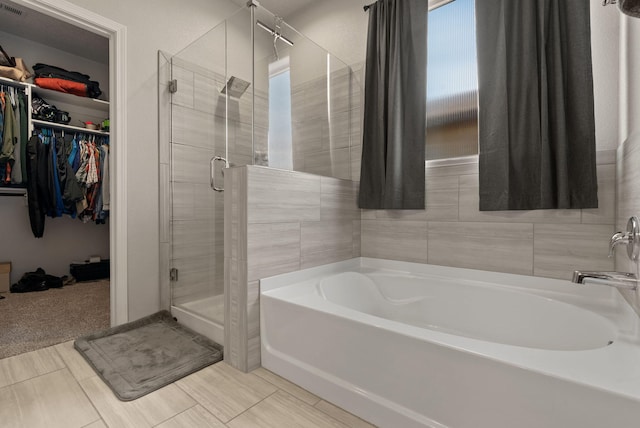 full bath with a shower stall, a walk in closet, and a garden tub