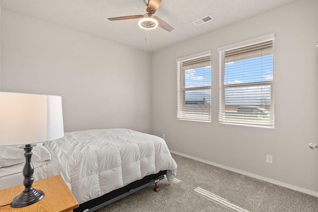 carpeted bedroom with visible vents, baseboards, and ceiling fan