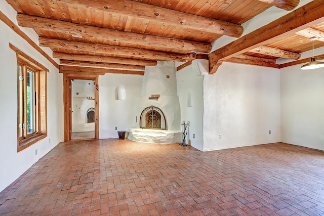 545 Atrisco Dr NW, Albuquerque, NM 87105 - unfurnished living room with wood ceiling, brick floor, a fireplace, and beamed ceiling