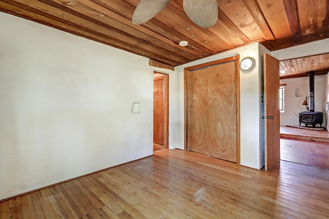 545 Atrisco Dr NW, Albuquerque, NM 87105 - empty room featuring wooden ceiling, light wood-style flooring, and a wood stove