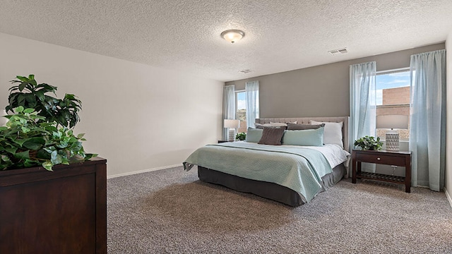 carpeted bedroom with baseboards, a textured ceiling, and visible vents