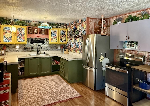 10 Cliffside Dr, Ramah, NM 87321 - kitchen featuring a textured ceiling, appliances with stainless steel finishes, a sink, green cabinets, and light wood finished floors