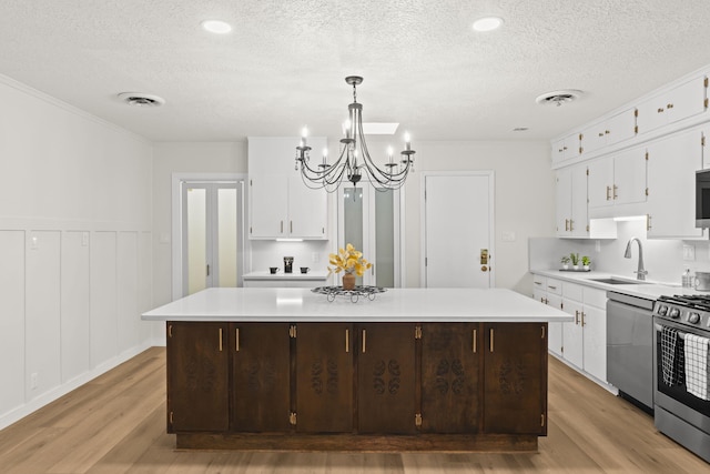 kitchen with a sink, appliances with stainless steel finishes, light wood-style floors, and a textured ceiling