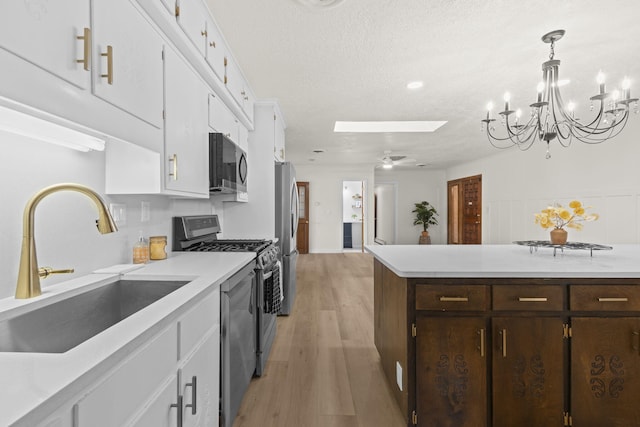 kitchen featuring dark brown cabinetry, appliances with stainless steel finishes, a sink, light countertops, and white cabinetry