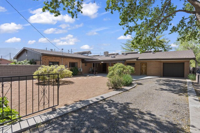 mid-century home with brick siding, an attached garage, fence, and driveway