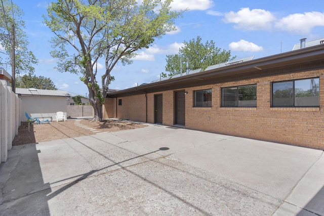 back of house with brick siding, a patio, and fence