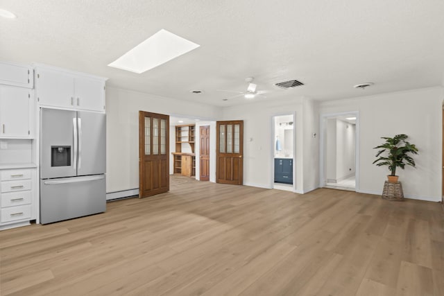 unfurnished living room featuring visible vents, light wood-style floors, ceiling fan, a baseboard radiator, and a skylight
