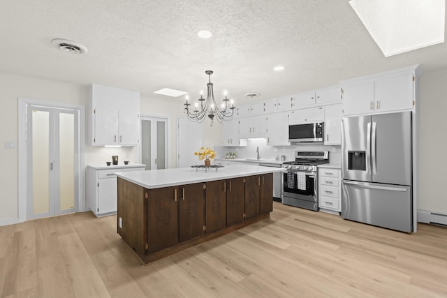 kitchen featuring light wood-style floors, appliances with stainless steel finishes, a textured ceiling, and a notable chandelier