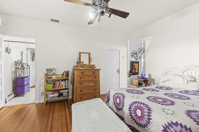 bedroom with visible vents, a baseboard radiator, ceiling fan, and wood finished floors