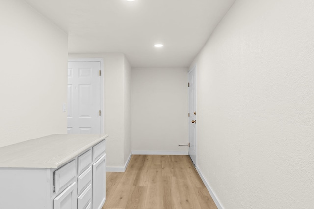 hallway with baseboards, recessed lighting, and light wood-style flooring