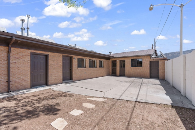rear view of property featuring brick siding, a patio area, and fence
