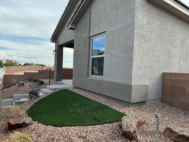 view of home's exterior with fence and stucco siding