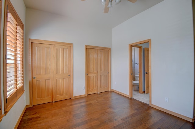 3728 Spyglass Loop SE, Rio Rancho, NM 87124 - unfurnished bedroom with baseboards, connected bathroom, a towering ceiling, wood finished floors, and multiple closets