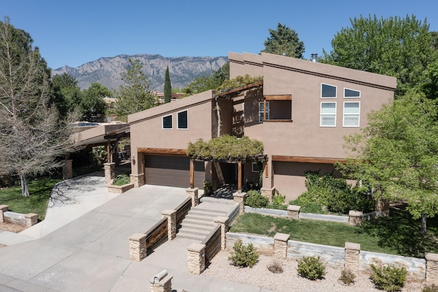 view of front of home with a mountain view, an attached garage, concrete driveway, and stucco siding